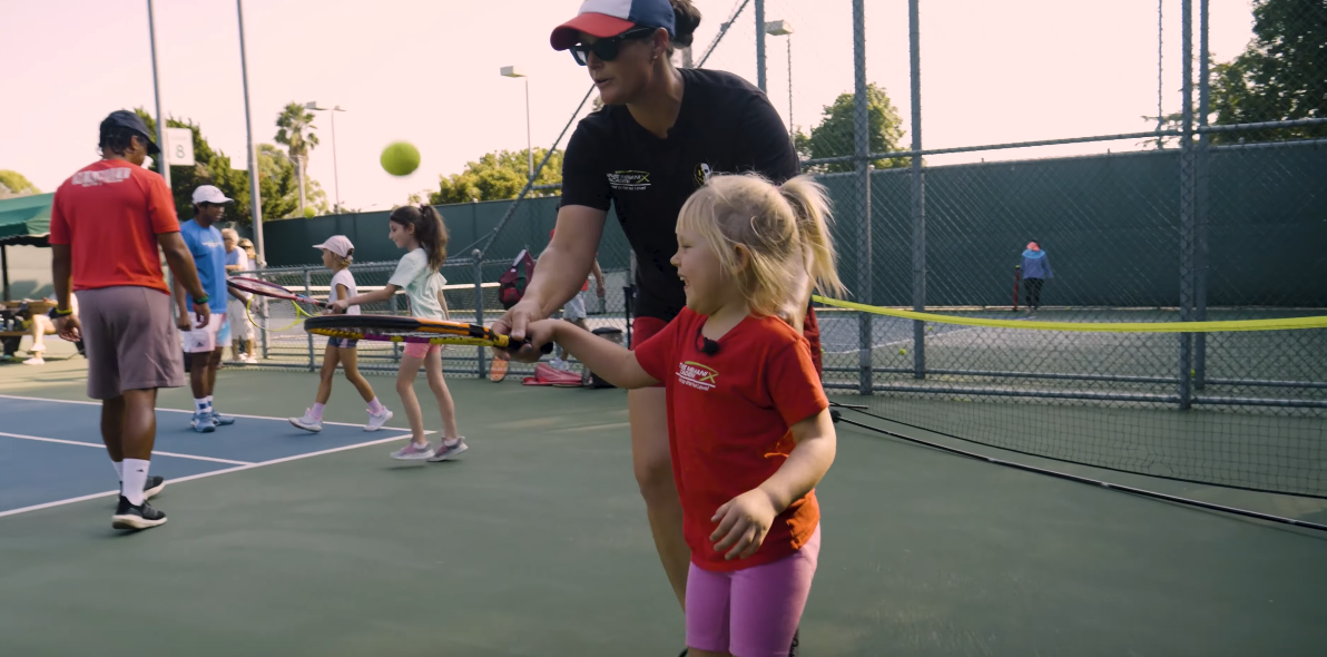 Child learning tennis with coach
