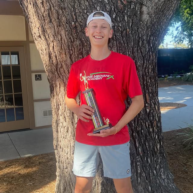 Student with trophy in front of tree