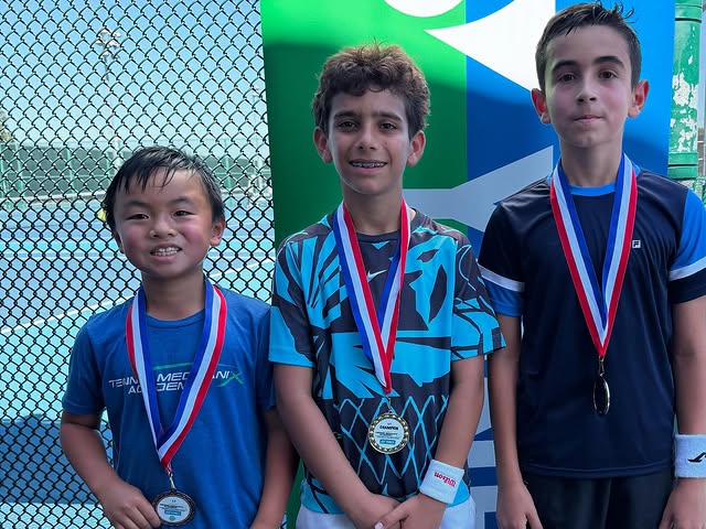 Three students with medals at a tournament
