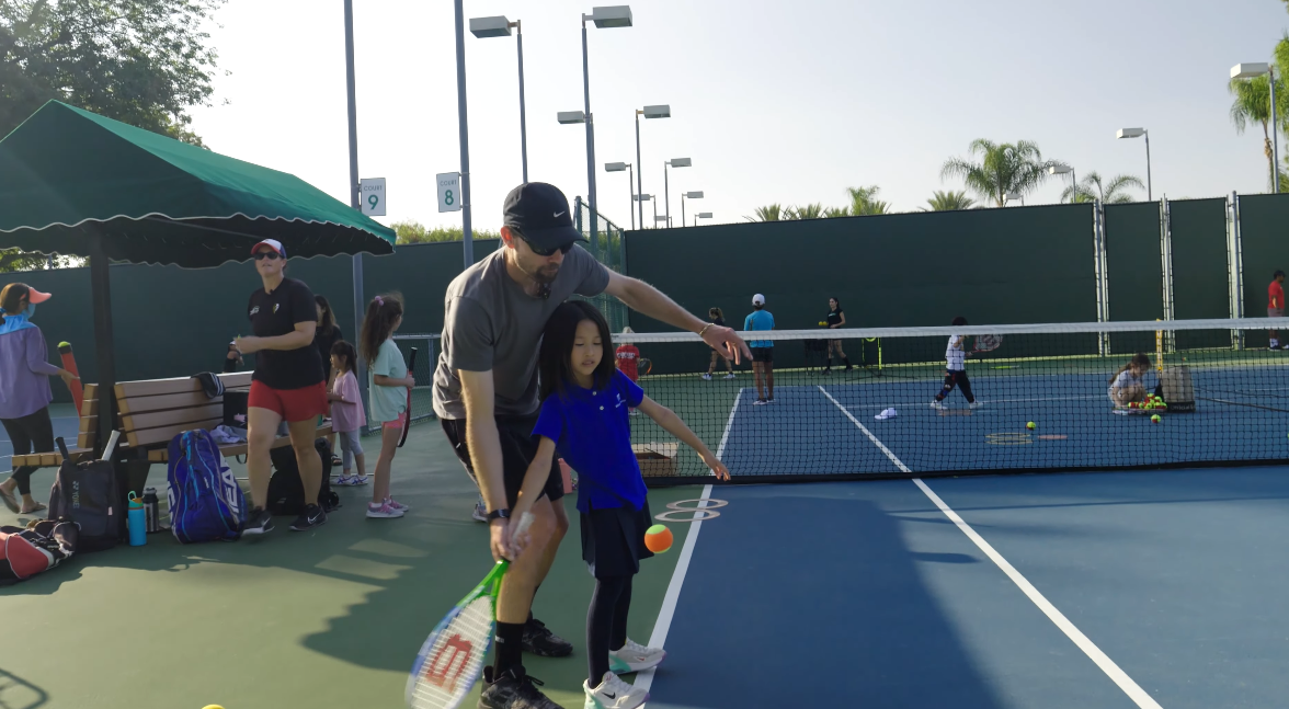 Coach teaching tennis to a student